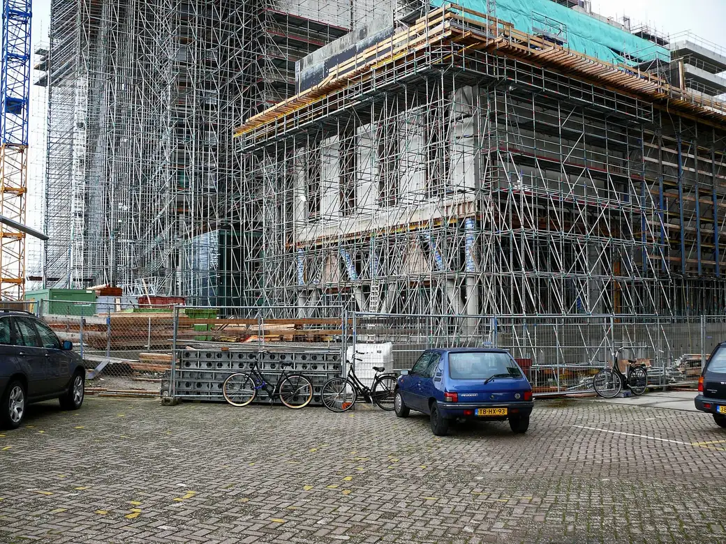 Fachada de um edifício em obra tomada por andaimes tubulares.
